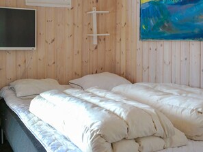 Un lit avec une literie blanche dans une pièce aux murs en bois.