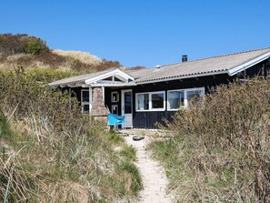 A coastal house with a sandy path leading to the entrance, surrounded by dense vegetation. - 6 Person Holiday Home in Saltum (Saltum)