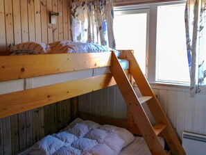 A bunk bed with a wooden ladder, a window with curtains, and a radiator. - 6 Person Holiday Home in Saltum (Saltum)