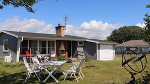En bostadsfastighet med en inglasad uteplats, utomhusmöbler och ett garage.
