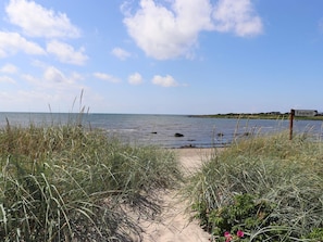 Ein Strandweg, der zum Meer führt, mit einem Schild, auf dem 'Toalett' steht.