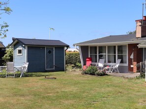 A house with a blue shed and a covered porch with chairs. - 5 Person Holiday Home in Traslovslage (Träslövsläge)