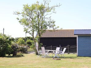 A clear outdoor area with a table and chairs, a tree, and a building with a tiled roof. - 5 Person Holiday Home in Traslovslage (Träslövsläge)