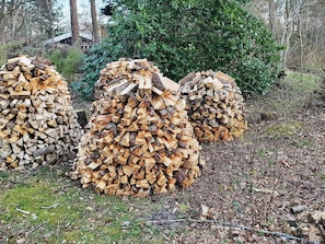 Three large stacks of cut wood logs in a natural outdoor setting.