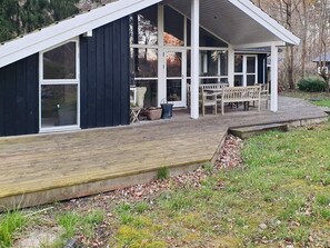 A house with a covered porch, large windows, and a wooden deck.