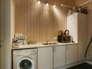 A compact kitchen with a washing machine, a sink, and wooden walls. - 4 Star Holiday Home in Vejby (Vejby)