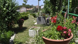 A garden with a variety of plants and flowers, a pathway, and a stone structure. - Apartments Profaca - Two Bedroom Apartment with Terrace (Rab)