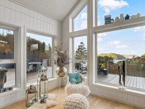 A spacious room with large windows offering a view of a deck and surrounding landscape. - 10 Person Holiday Home in Lyngdal (Lyngdal)