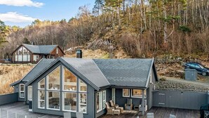 Una casa moderna con un'ampia terrazza, grandi finestre e un vialetto in pietra.