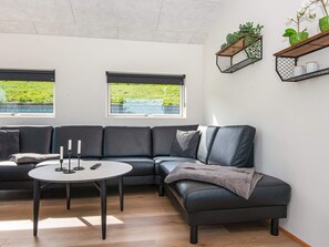 A modern living room with a sectional sofa, a round coffee table, and two windows with blinds. - 6 Person Holiday Home in Lemvig (Lemvig)