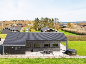 A modern house with a flat roof, a patio with outdoor furniture, and a view of the surrounding landscape.