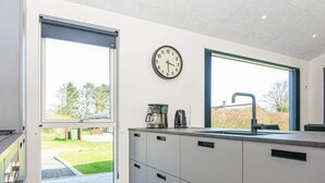 A modern kitchen with a built-in oven, a coffee maker, and a clock on the wall.