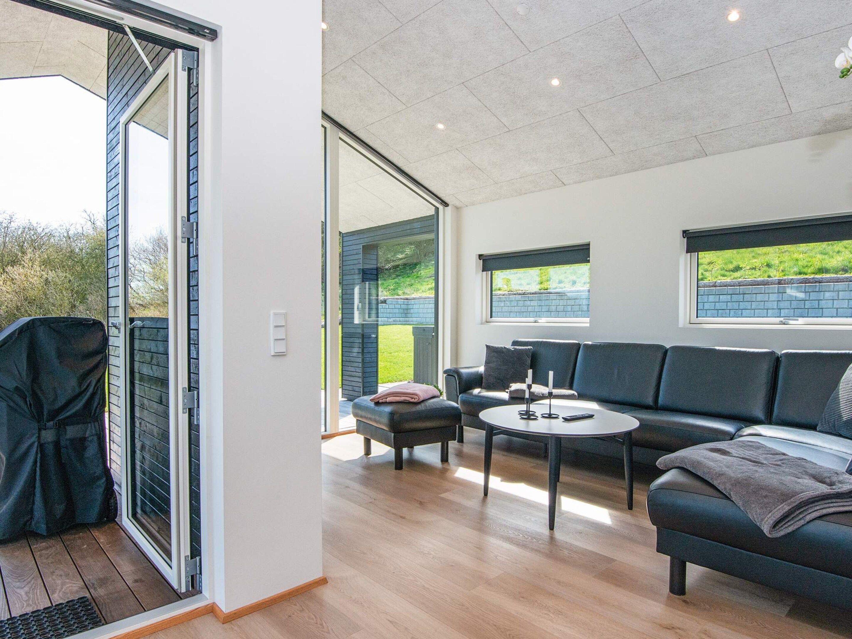 A modern living room with a sofa, a coffee table, and a sliding glass door leading to a balcony.