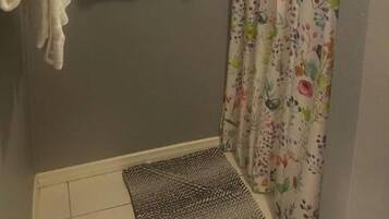 Une salle de bain avec un rideau de douche, deux serviettes blanches et une petite fenêtre.