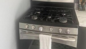 Una cocina con microondas de acero inoxidable, estufa a gas y horno de acero inoxidable.