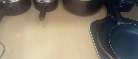 Una encimera de cocina con tres ollas y una sartén.