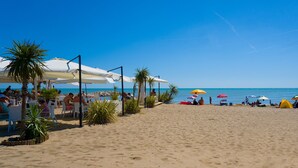 A beach with white umbrellas, palm trees, and people relaxing.