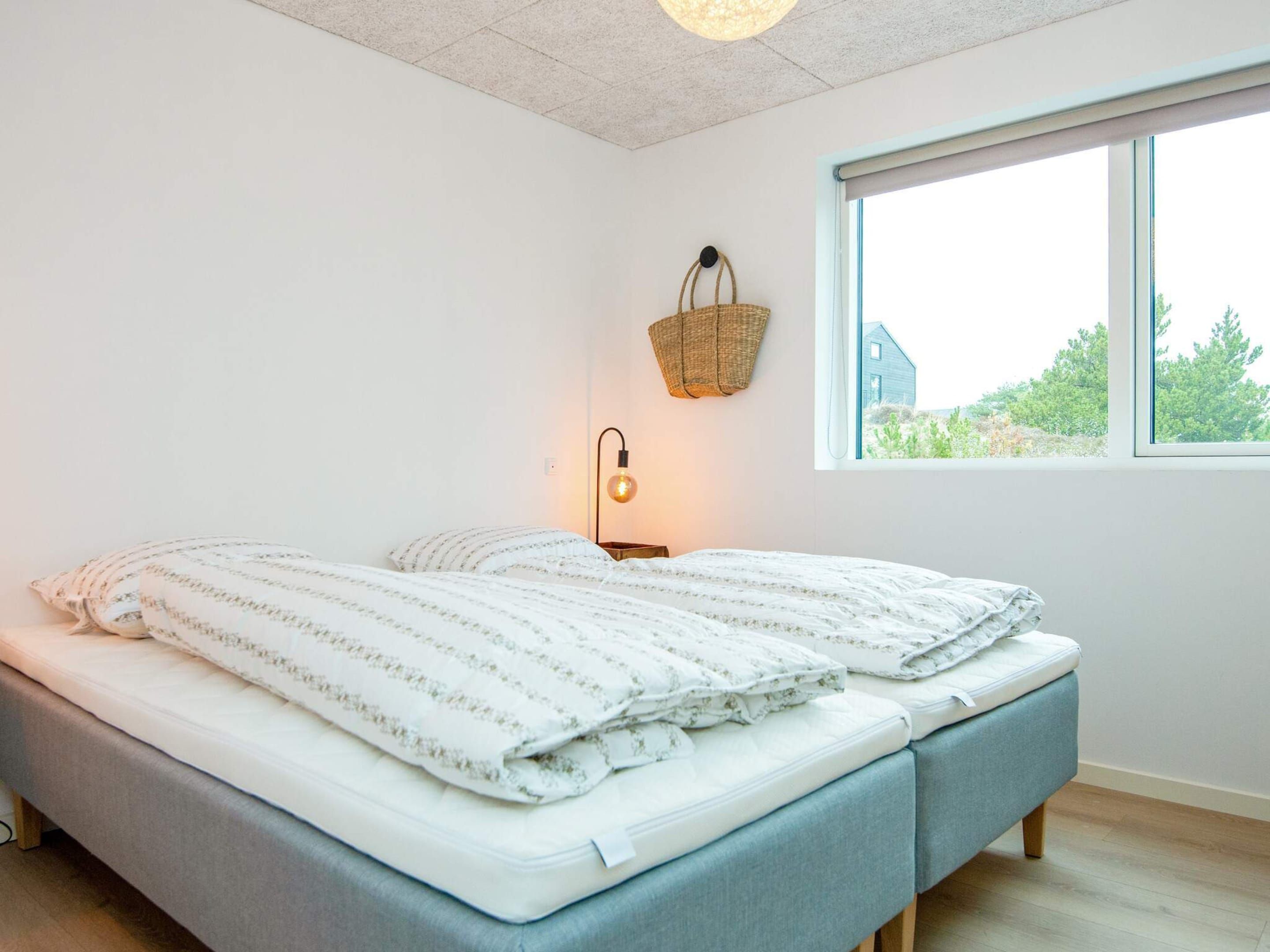 Ein Schlafzimmer mit einem Bett, einer Nachttischlampe, einem Fenster und einer hängenden Ampel.