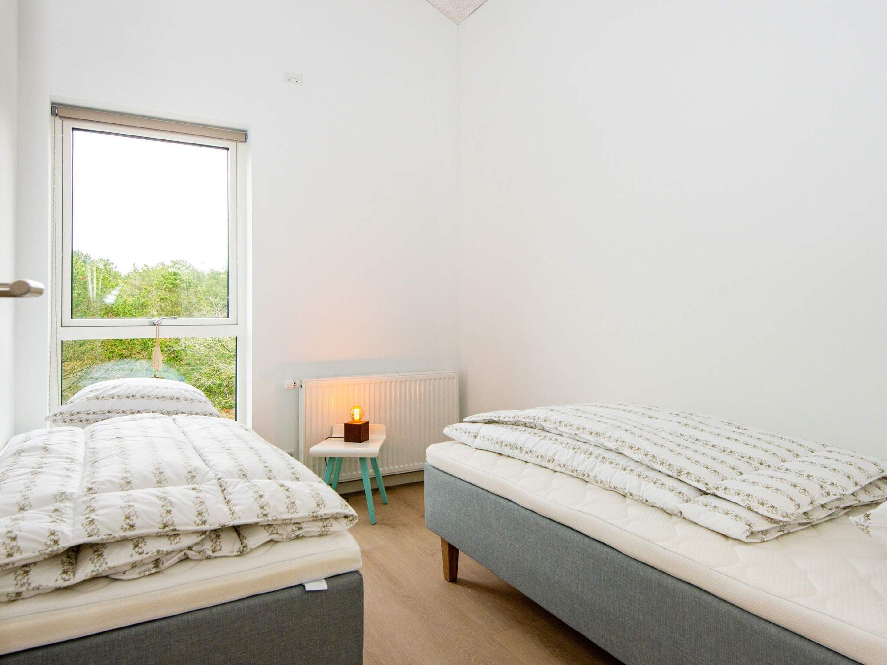 Ein Schlafzimmer mit zwei Betten, einem Heizkörper, einem kleinen Tisch und einem Fenster mit Blick.