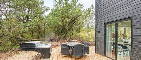 A wooden deck with outdoor furniture, surrounded by trees.