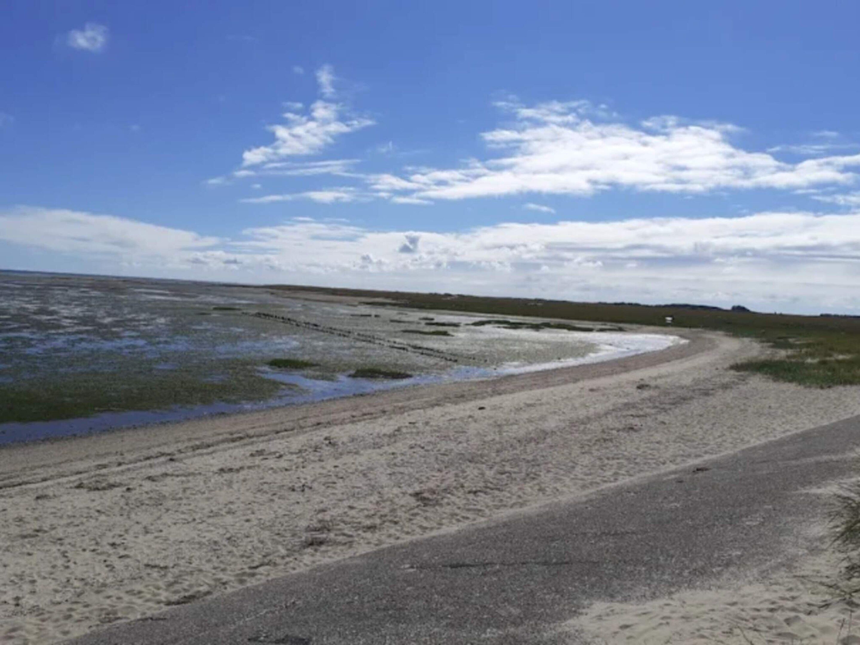 A coastal road with sandy terrain and a clear sky.