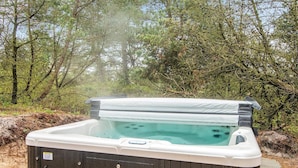 Un bain à remous installé à l’extérieur, avec une terrasse en bois et un environnement naturel.