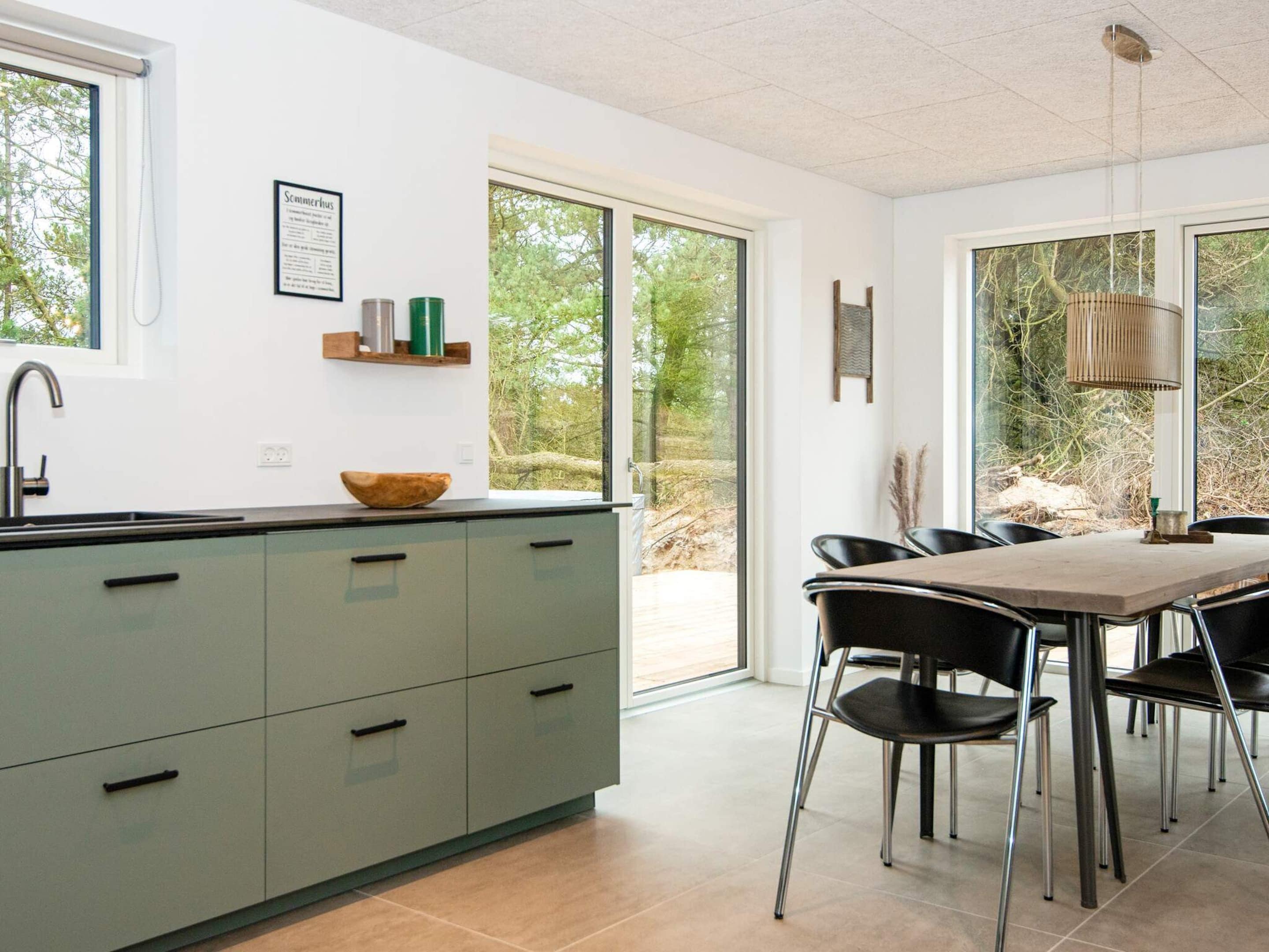 Eine moderne Küche mit einem großen Fenster, einem Essbereich mit Stühlen und einem Tisch.