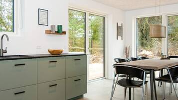 Eine moderne Küche mit einem großen Fenster, einem Essbereich mit Stühlen und einem Tisch.