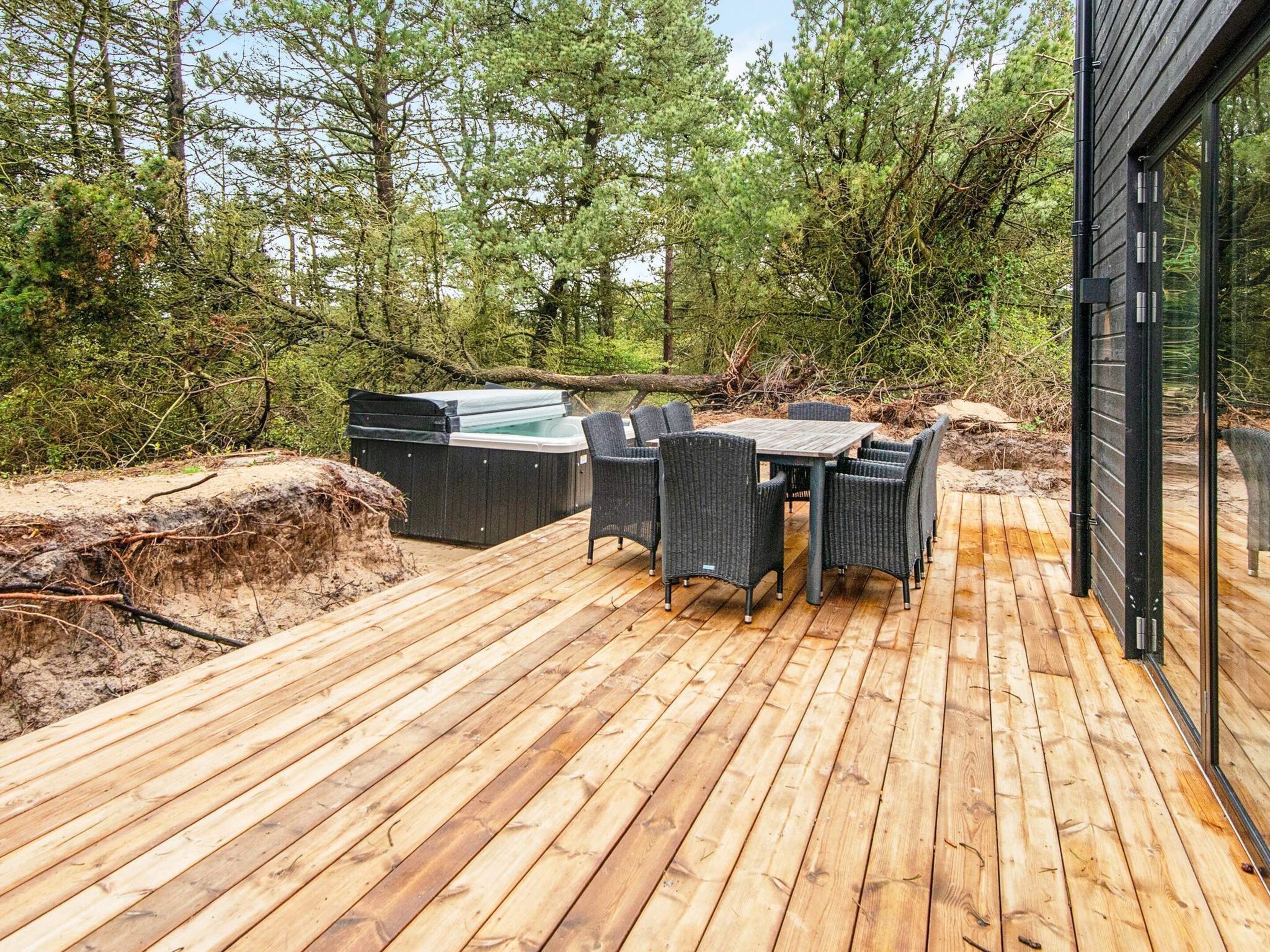Een houten terras met buitenmeubilair en een jacuzzi.