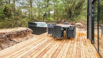 A wooden deck with outdoor furniture and a hot tub.