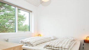 Une chambre à coucher avec un lit, un bureau, une fenêtre et une table de chevet avec une lampe.