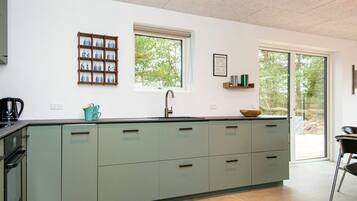 Eine moderne Küche mit einer Kochinsel, einem Fenster und Blick ins Freie.
