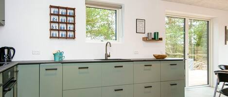 A modern kitchen with a central island, a window, and a view of the outdoors.