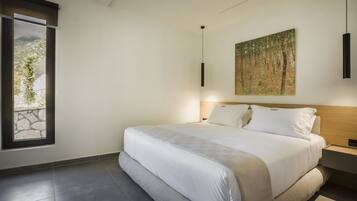 A modern bedroom with a large bed, a painting on the wall, and a window with a view.