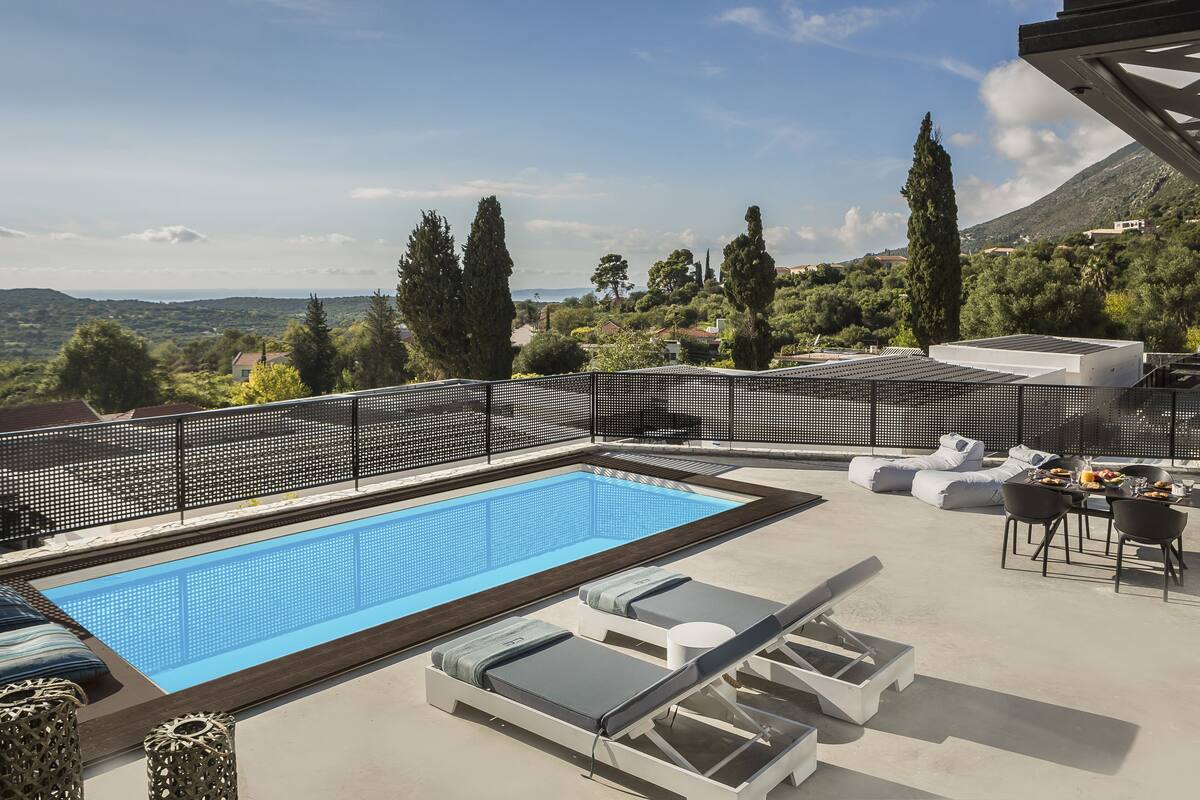 A rooftop pool area with a view of the landscape, including trees and distant hills.