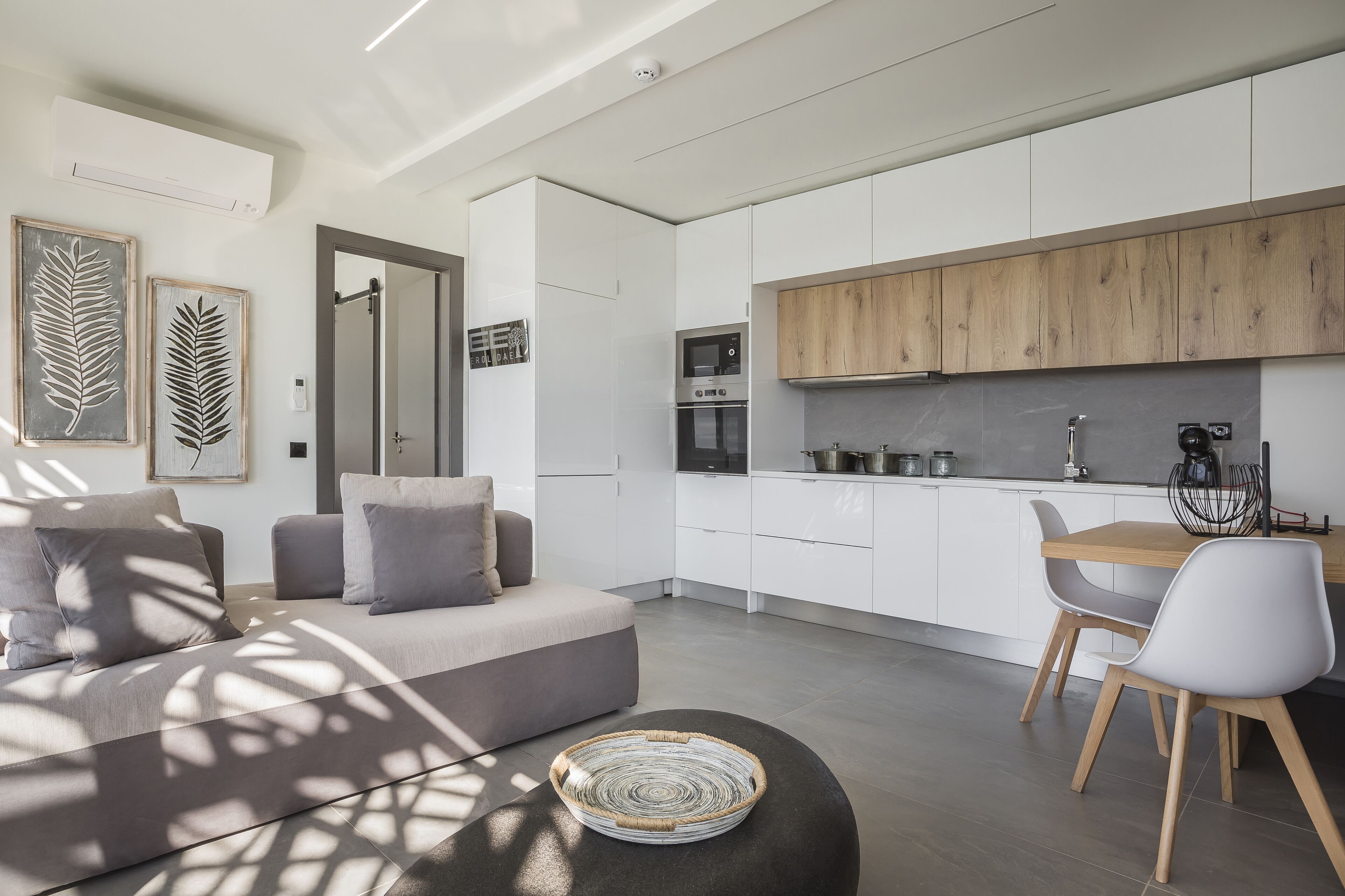 A modern kitchen with white cabinets, a wooden countertop, and a dining area with a table and chairs.