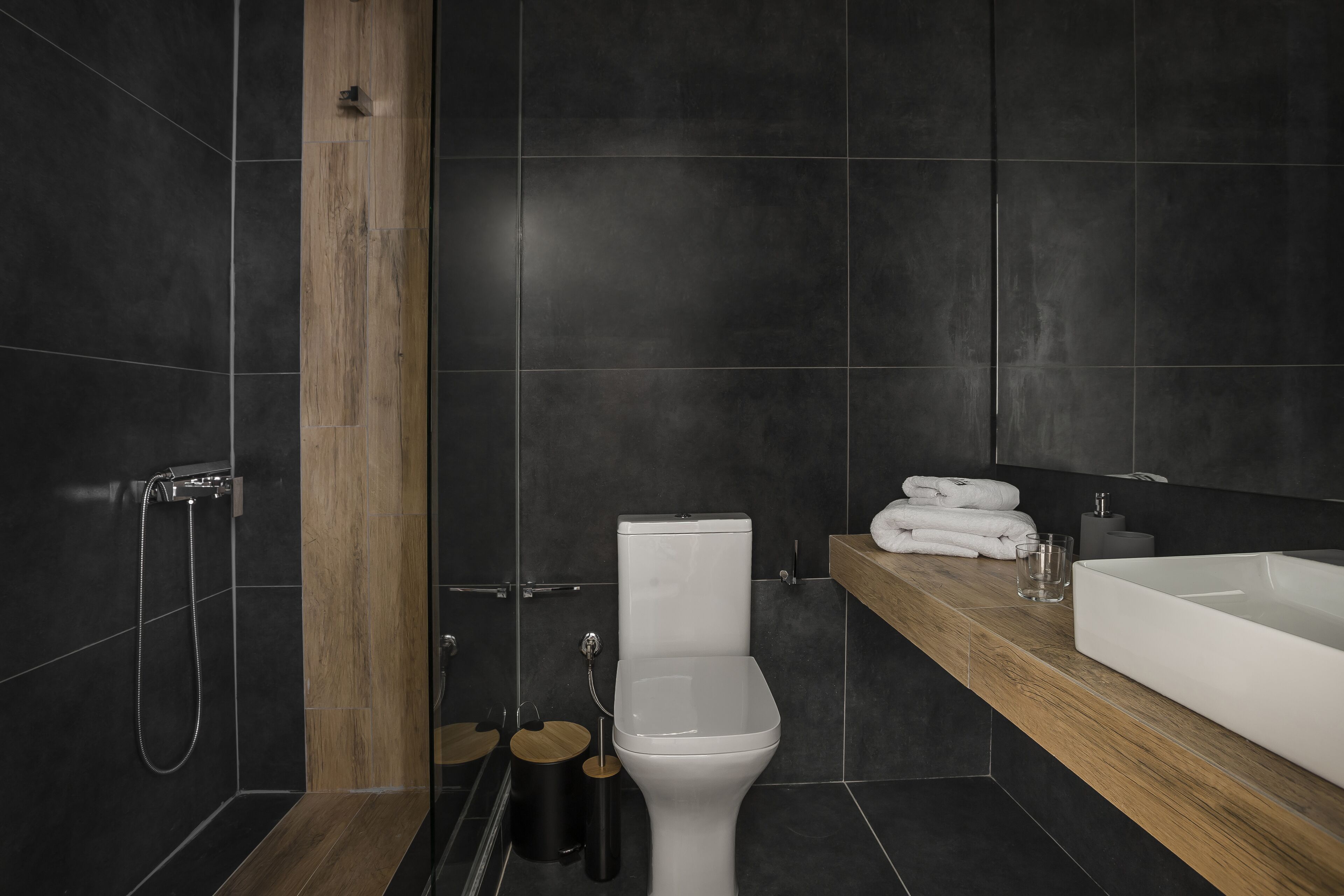 A modern bathroom with a wooden vanity, a white sink, and a toilet.