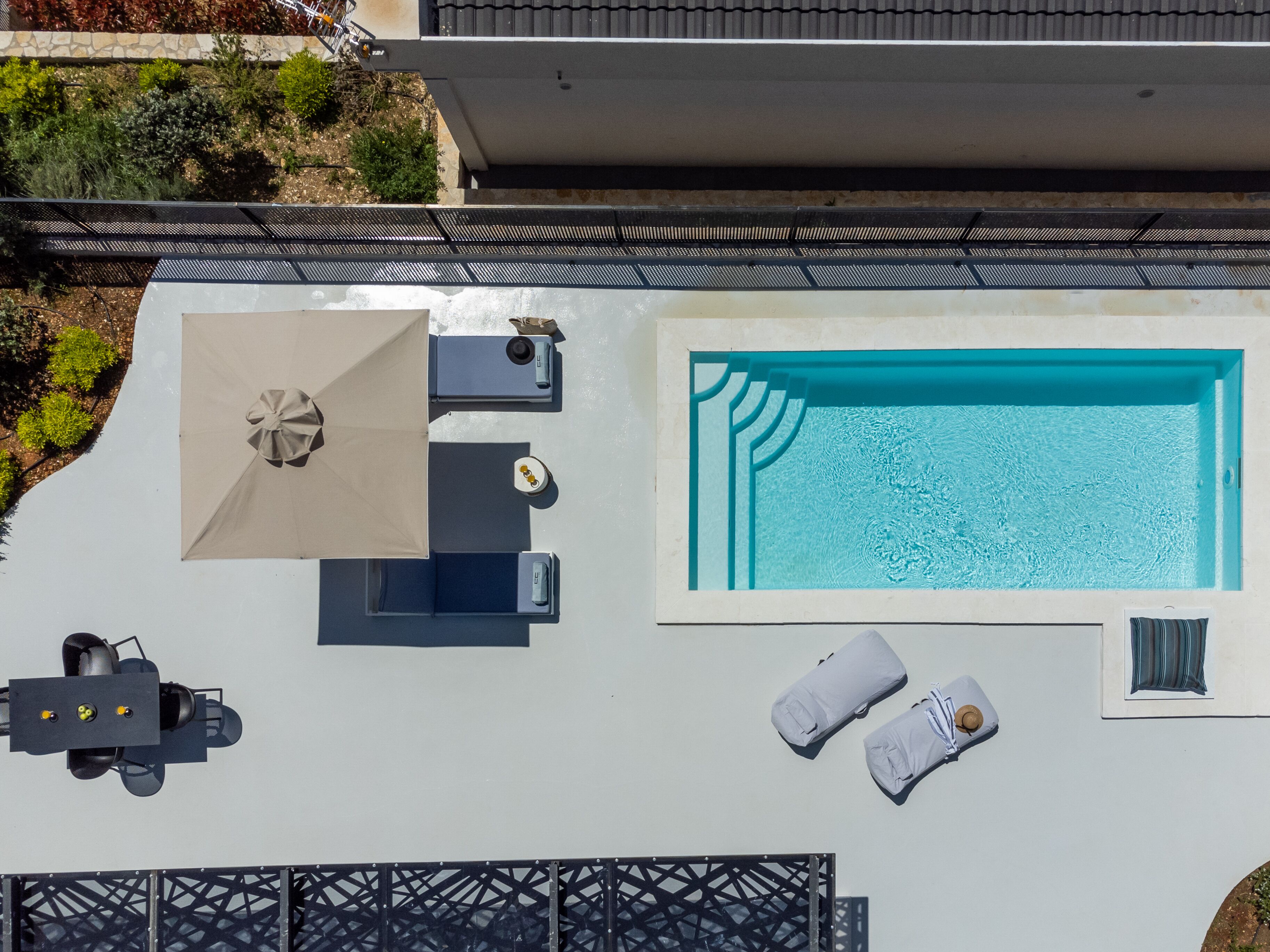 Vista aérea de una piscina en la azotea con un sillón de sol y una mesa con sillas.