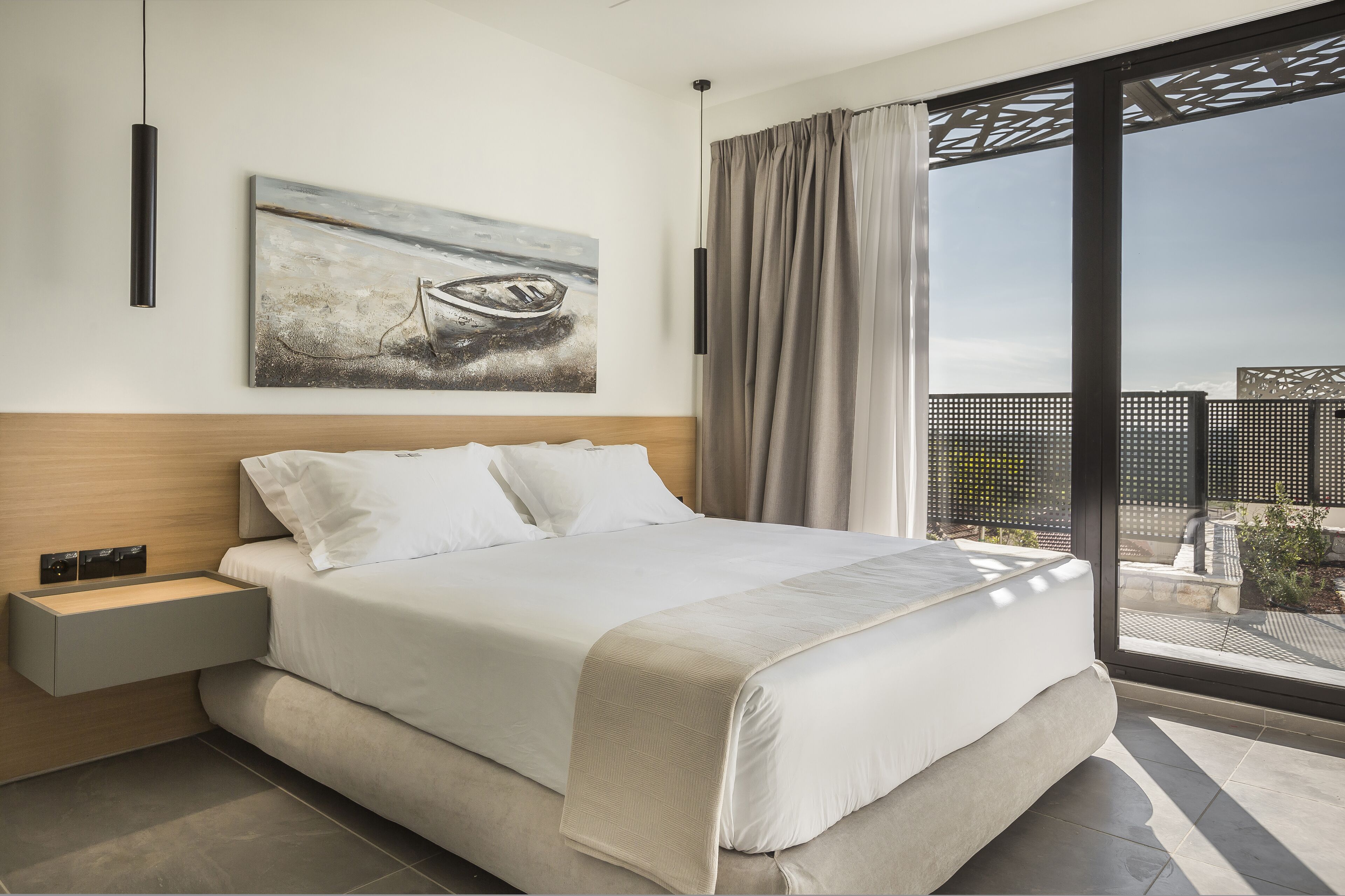 Un dormitorio moderno con una cama grande, una mesita de noche, una obra de arte en la pared y vistas por una ventana amplia.