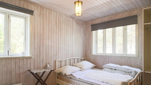 A single-bed room with wooden walls and a sloped ceiling. There is a window on the left and a large window on the right. - 6 Person Holiday Home in Sjaellands Odde-by Traum (Sjællands Odde)