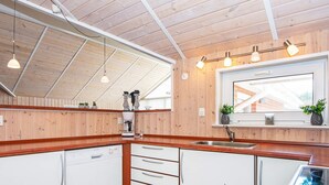 Eine moderne Küche mit Holzverkleidung, einem eingebauten Geschirrspüler, einer Kaffeemaschine und einem Fenster mit Blick auf ein Haus.