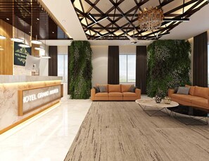 Un hall d’hôtel moderne comprenant un comptoir d’accueil, un ensemble de canapés, une table basse et un lustre.
