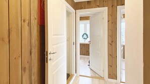 A hallway with wooden walls and white doors leading to a room with a window and a wreath on the sill. - 4 Star Holiday Home in Rauland (Vinje)