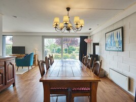 A dining room with a wooden table, chairs, a chandelier, a television, and a fireplace.