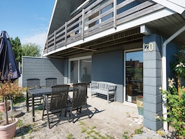 Un patio con mobiliario exterior, una terraza de madera y el número 70.