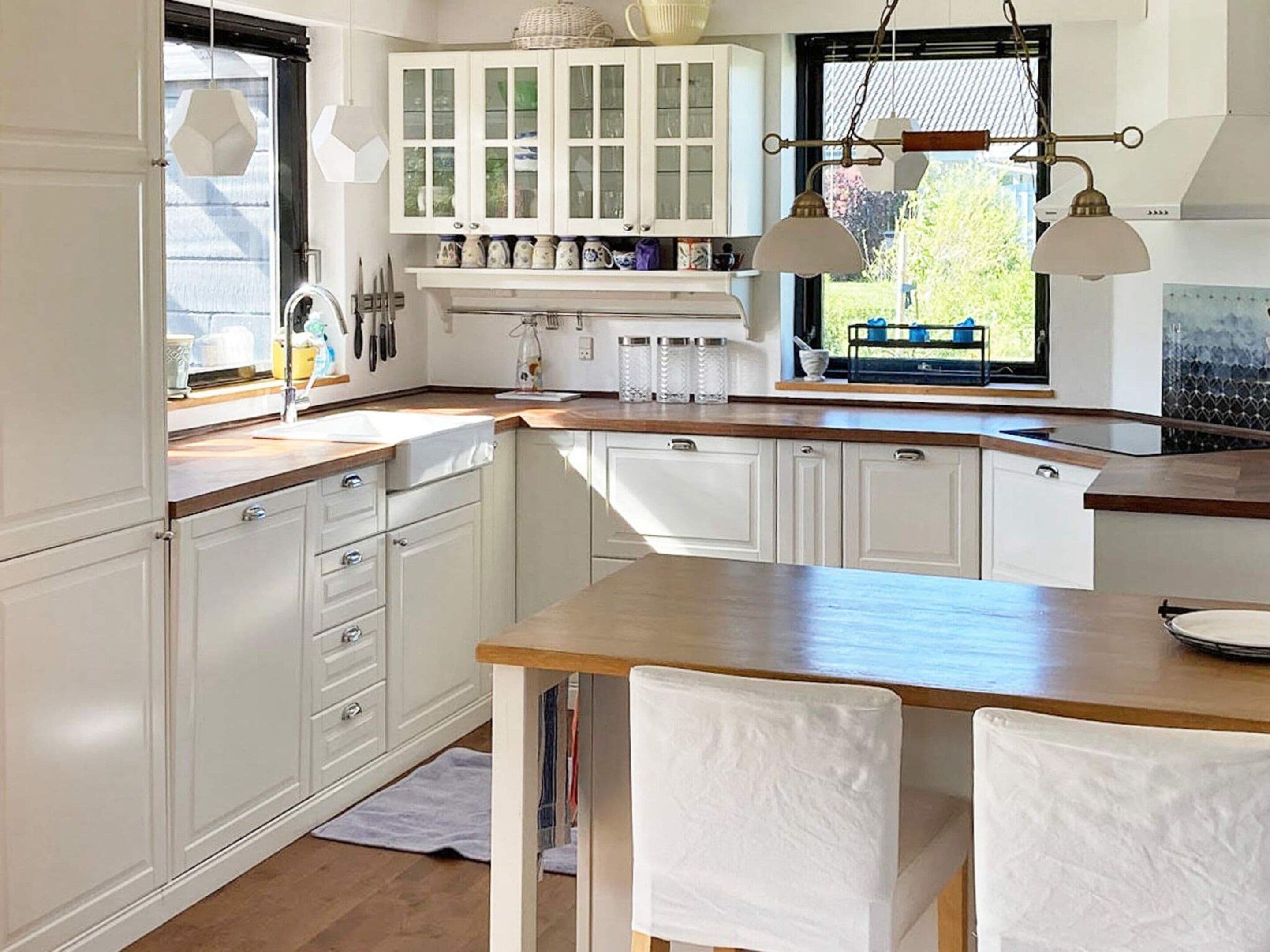 A kitchen with white cabinetry, a wooden countertop, and pendant lighting.