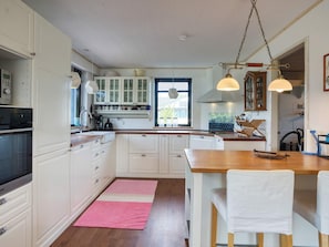 A kitchen with white cabinets, a wooden countertop, a pink rug, and pendant lights. - 7 Person Holiday Home in Nakskov (Nakskov)