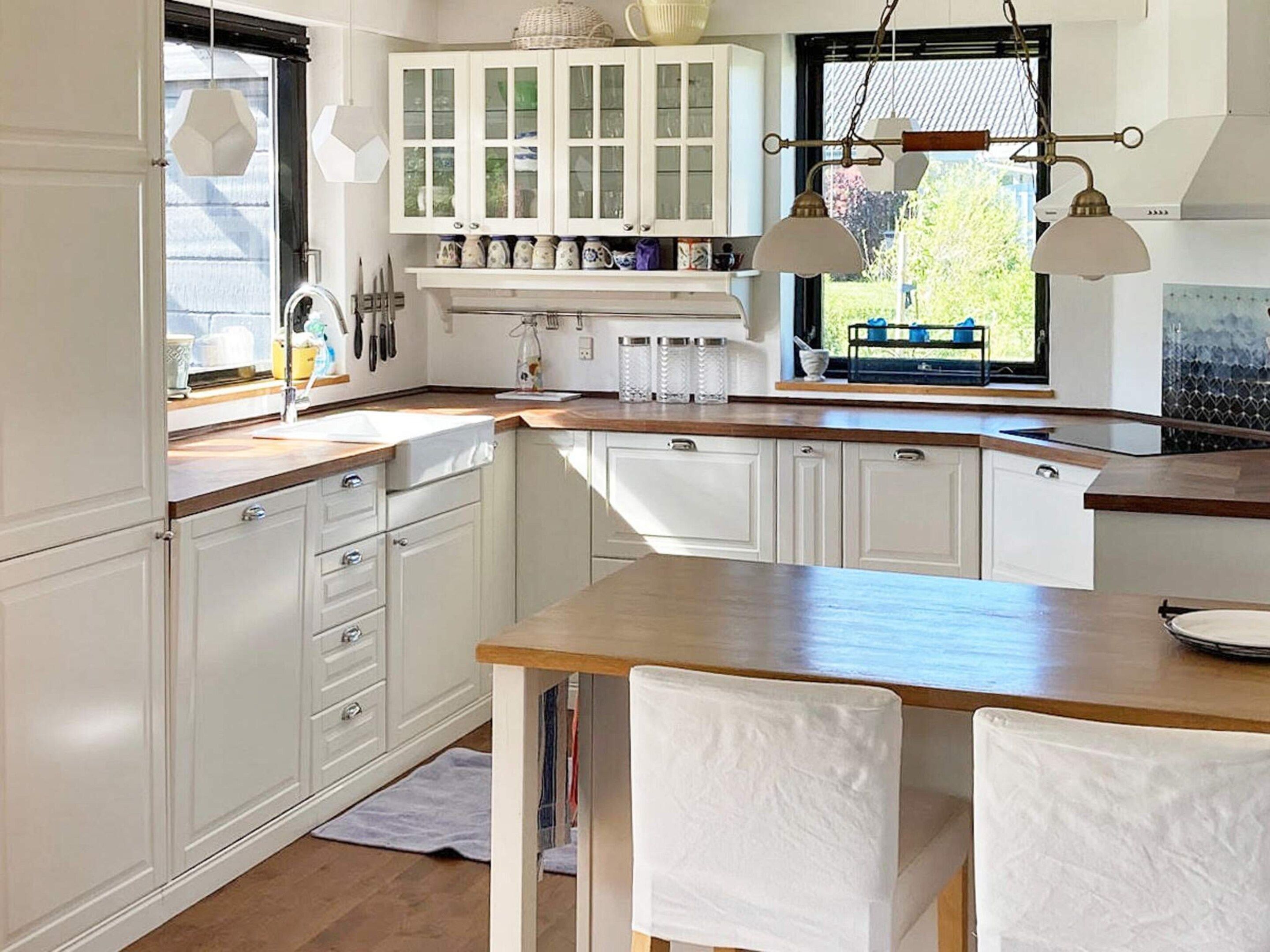 Een keuken met witte kasten, een houten aanrecht en hanglampen.