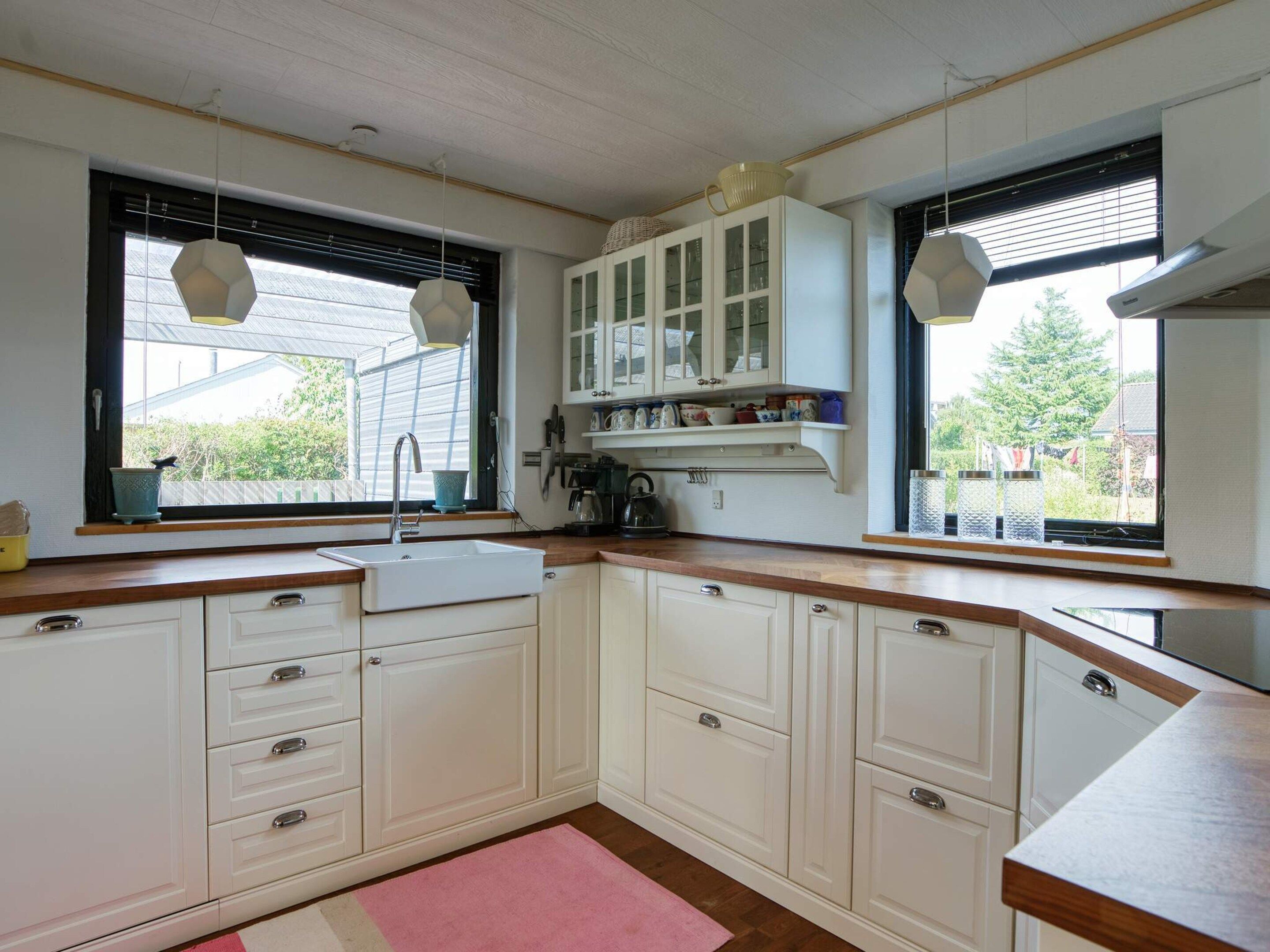 A kitchen with white cabinets, a sink, and a window with a view of greenery.