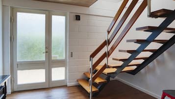A modern interior with a wooden staircase, a sliding glass door, and a red chair.